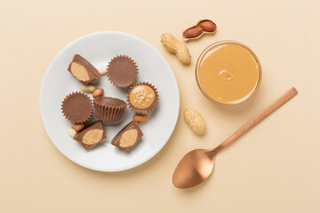 Delicious peanut butter cups with nuts on color background, top view