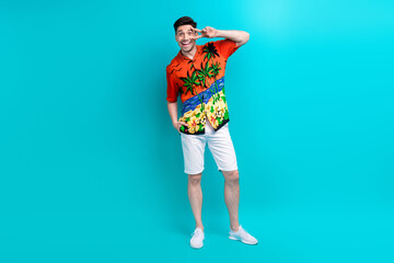 Fototapeta premium Full size photo of cheerful funky impressed guy wear tropical shirt stylish shorts show v-sign on eye isolated on blue color background