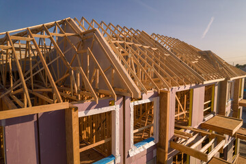Roofing construction aerial. Wooden roof frame installation of the house. Truss beams structures on...