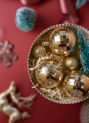 Christmas decorations in the round gift box with fir tree on the red background. Close up winter holidays greeting card.