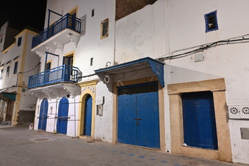 Fototapeta na wymiar Beleuchtete historische Altstadthäuser in Essaouira in Marokko. Menschenleere Gasse, da kurz vor Sonnenaufgang 