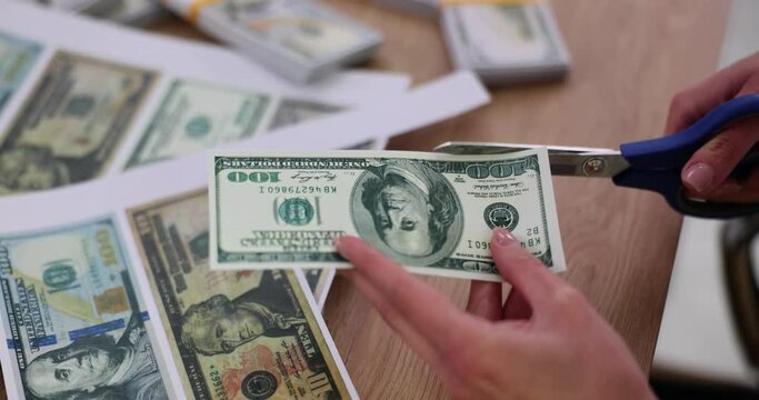 Criminal counterfeiter cuts dollar bills with scissors printed on printer closeup