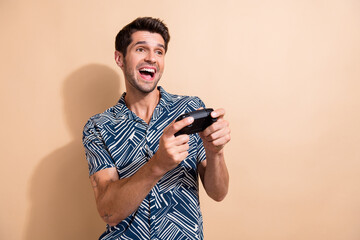 Photo of crazy young guy playing video games holding joystick addicted gamer enjoying weekend...