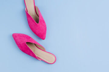A pair of mules shoes on bllue background. Pink women’s flat shoes. Fashion ballet shoes,...