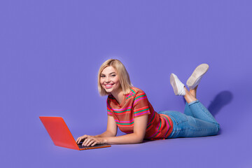 Full body photo of student girl studying during vacation in another country lying floor with computer isolated on purple color background