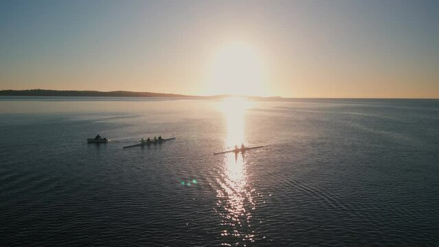 Aerial view of seascape and rowing sport boats on calm ocean water with sunrise.