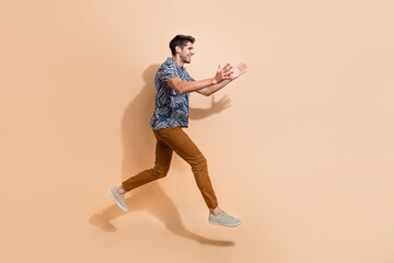 Fototapeta na wymiar Full body photo of energetic person jump over floor trying to catch discount promo code in empty space isolated on beige color background