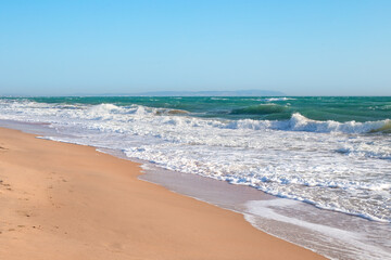 Seascape. Blue Sea with foamy waves and sandy coast.