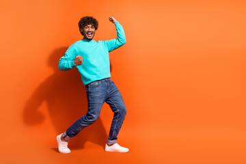 Fototapeta na wymiar Full size photo of delighted funky person raise fists success achieve empty space isolated on orange color background