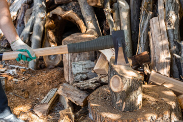 A man chops wood with an ax and cleaver. Preparing fuel for the winter.