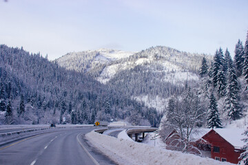 Fototapeta na wymiar Steep highway among snow-capped mountains on a cloudy winter day. American highways