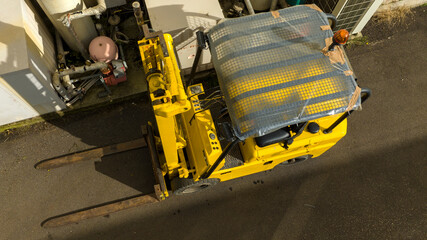 Aerial view of a yellow industrial forklift. There is no one there and the factory is empty.