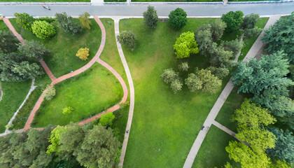 urban park with meadow trees and paths top view aerial photo from flying drone of a city park with walking path and green zone trees in evening time - obrazy, fototapety, plakaty