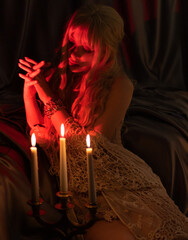 beautiful girl in a corset sits on the floor in the bedroom. admiring the dim candlelight. vintage...
