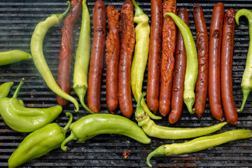 Green peppers and pork sausages on the barbecue grill. Fresh anaheim chili peppers roasting over a charcoal fire.  Cooking peppers at the barbecue.  Cayenne pepper.