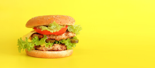 Cheeseburger on a yellow background. Juicy tasty burger on a bright background, side view. Fast food. Copy space