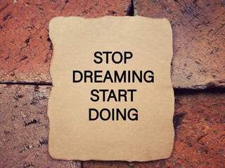 Motivational and inspirational wording. STOP DREAMING START DOING written on a paper. With blurred...