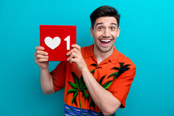 Portrait of impressed ecstatic guy wear tropical shirt hold social media like in arms astonished staring isolated on blue color background