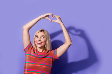 Fototapeta premium Portrait of young dreamy pretty girlfriend show heart symbol looking curious valentine day greetings isolated on violet color background