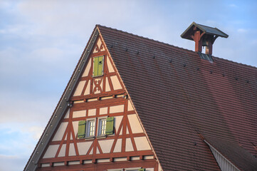 Giebelseite eines Fachwerkhauses mit Glockenturm und grünen Fensterladen vor blauem Himmel am alten Rathaus in Neckartenzlingen