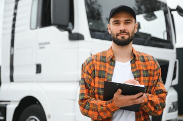 Truck driver checking shipment list while standing on parking lot of distribution warehouse