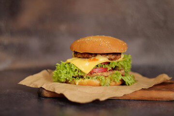 Double cheeseburger on a gray background. Juicy tasty burger on craft paper, side view. Fast food. Copy space