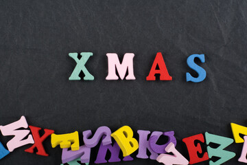 XMAS word on black board background composed from colorful abc alphabet block wooden letters, copy space for ad text. Learning english concept.
