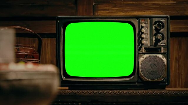 Retro TV Green Screen Turns On Television Room Zoom In Old Style. Old vintage television with green screen, for replacement, inside a house. Zoom in