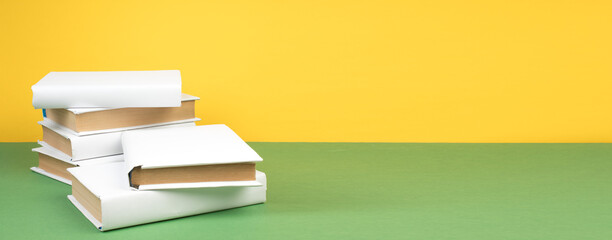 Books stacking. Open hardback books on wooden table and green background. Back to school. Copy space for ad text. Banner