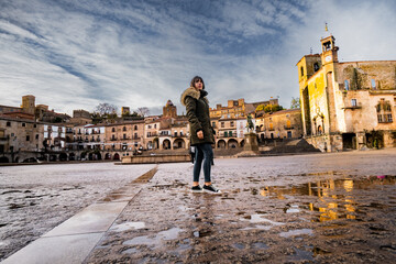 Traveler admires Trujillo's historic square, bathed in autumn's warm hues.