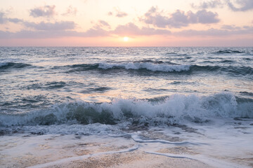 sun sets on a dramatic cloudy sky over the Mediterranean Sea horizon with a warm, golden glow. The sea's waves  magical tranquil seascape