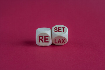 Turned a wooden cube and changes the red word relax to reset. Beautiful red background. Business, relax and reset concept. Copy space.