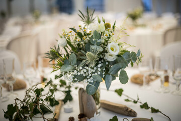 Un bouquet de fleur de mariage posé sur une table dressée avec une nappe blanche et de la porcelaine