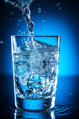 Cold water is poured into a glass of water, with blue background and beautiful lighting