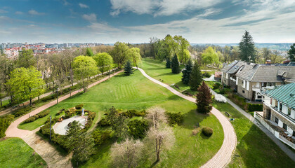 Fototapeta premium aerial top view of spring park landscape with green trees lawns and footpath park is surrounded by with houses green space city park aerial drone view high above