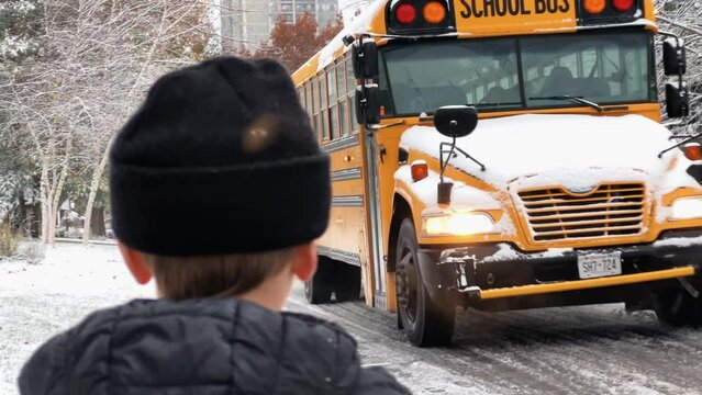 Young boy waits for the school bus in the winter
