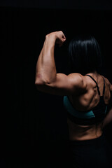 Fototapeta na wymiar person training. female athlete shows her biceps on a black background in a top and shorts