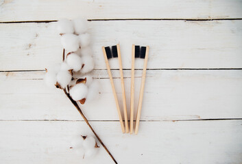 Eco-friendly bamboo toothbrushes and cotton flowers on a wooden background. Zero waste. The concept of natural organic cosmetics for the bathroom.