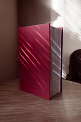 Red hardcover book standing vertically on a table at home