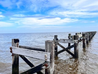 A weathered and broken down pier leading into the Gulf of Mexico,