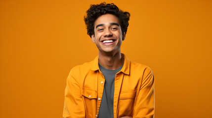 a young Indian male presenter smiling in front of a bright solid colored background - obrazy, fototapety, plakaty