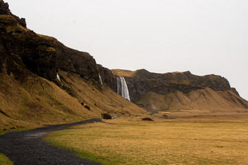 Stunning waterfall with black stone path leading to it on alien like landscape
