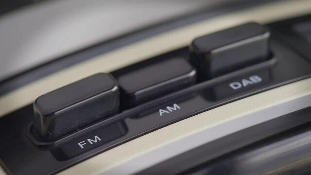 Vintage Radio buttons AM AF DAB switching by finger to change channels in a close up mode 