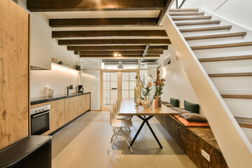 a kitchen and dining area in a loft style apartment with wooden stairs leading up to the second...