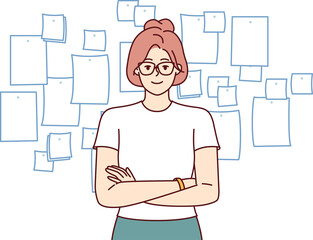 Confident business woman manager stands with arms crossed near kanban board and looks at screen