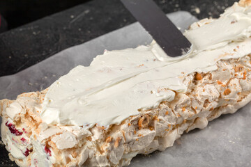 Pastry chef smears cream on meringue roll