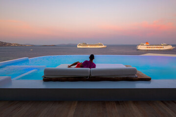 Man relaxes on the sunbed during sunset time at Mykonos, Greece