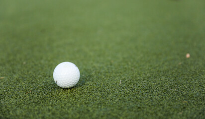 golf ball on the green, poised to sink into the hole, with the flag fluttering in the breeze,...