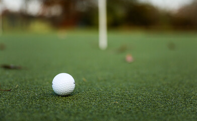 golf ball on the green, poised to sink into the hole, with the flag fluttering in the breeze, epitomizing precision and victory