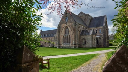 Pluscarden Abbey Monastery with a cloudy blue sky in the background in Pluscarden, Scotland